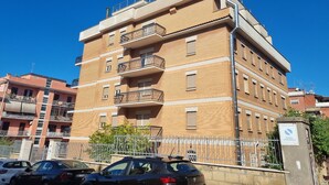 A multi-story residential building with balconies, a gated entrance, and a clear blue sky. - Palazzo Sant'Antonio Roma (Rome)