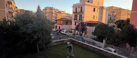 A courtyard with a statue, a bench, and a small garden area surrounded by buildings.