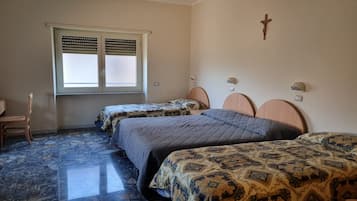 A bedroom with two beds, a window with blinds, a wooden cross on the wall, and a marble floor.