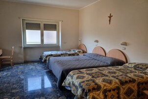 A bedroom with two beds, a window with blinds, a wooden cross on the wall, and a marble floor.