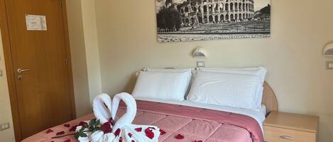 Habitación de hotel con cama, mesita de noche, lámpara de pared y puerta con un cartel.
