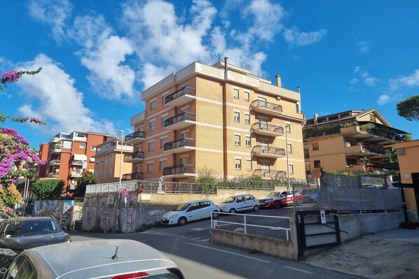 A multi-story residential building with balconies, a parking area, and a clear blue sky. - Palazzo Sant'Antonio Roma (Rome)