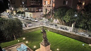 A courtyard with a statue, outdoor seating, and a view of parked cars and buildings. - Palazzo Sant'Antonio Roma (Rome)