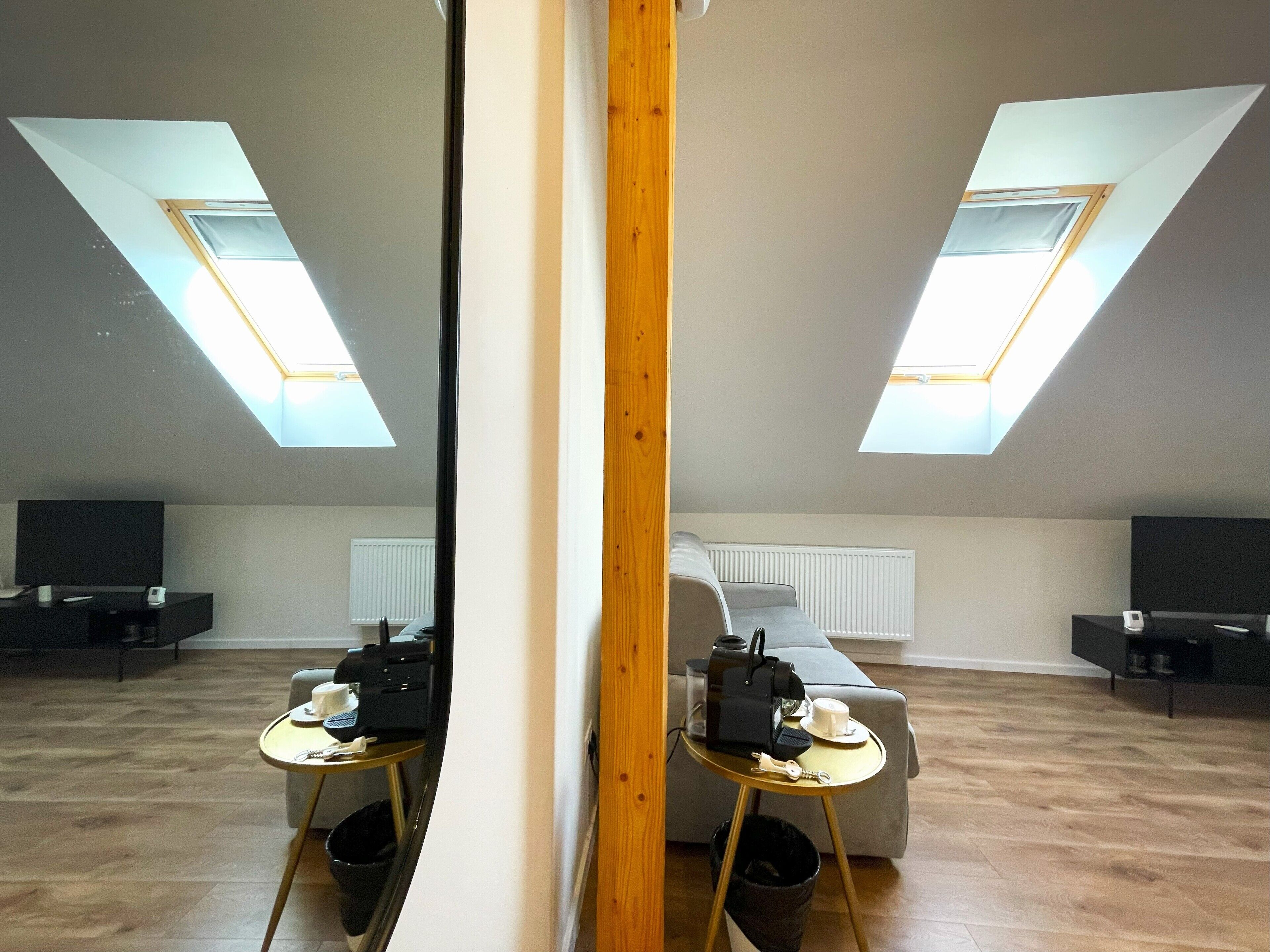 Un appartement moderne de style « loft », doté de fenêtres de toit, d’un canapé, d’une table basse et d’un téléviseur.