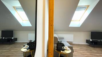 Un appartement moderne de style « loft », doté de fenêtres de toit, d’un canapé, d’une table basse et d’un téléviseur.