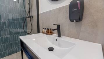 Une salle de bain moderne avec un lavabo blanc, un robinet noir et un distributeur de savon fixé au mur.