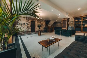 Un salón moderno con pared de ladrillo, una escalera, un sofá verde y una mesa de centro de madera.