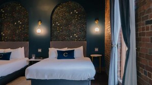 Een hotelkamer met twee bedden, een bakstenen muur en decoratieve bloemkunst op de muur.