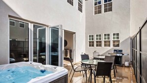 A hot tub, outdoor dining area, and a grill in a covered patio. - The Hudson: Dog Friendly, Private Hot Tub, Community Pool + Hot Tub (Hurricane)