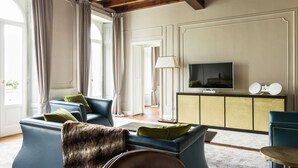 A living room with a blue sofa, a fur throw, and a television on a gold cabinet.
