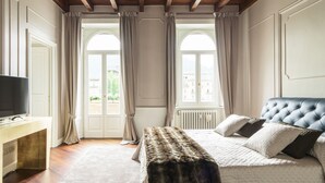 A bedroom with a bed, a TV, a desk, and a window with curtains.