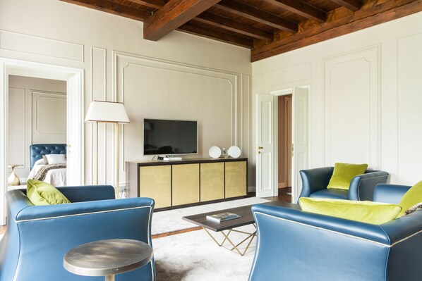 Una sala de estar con sofá, sillones, una mesa de centro y televisor.