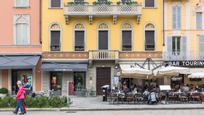 A yellow building with a bar named "BAR TOURING" and a store named "EMPORIO ARMANI".
