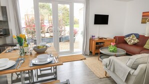 Una sala de estar moderna con comedor, sofá, televisor y vista al jardín.
