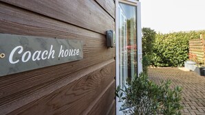 Pared exterior de madera con un letrero que dice "Coach House".