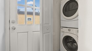 A laundry room with a white door, a window, and two stacked washing machines.