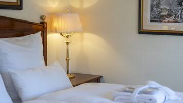 A hotel room with a neatly made bed, a bedside lamp, and framed artwork on the walls.