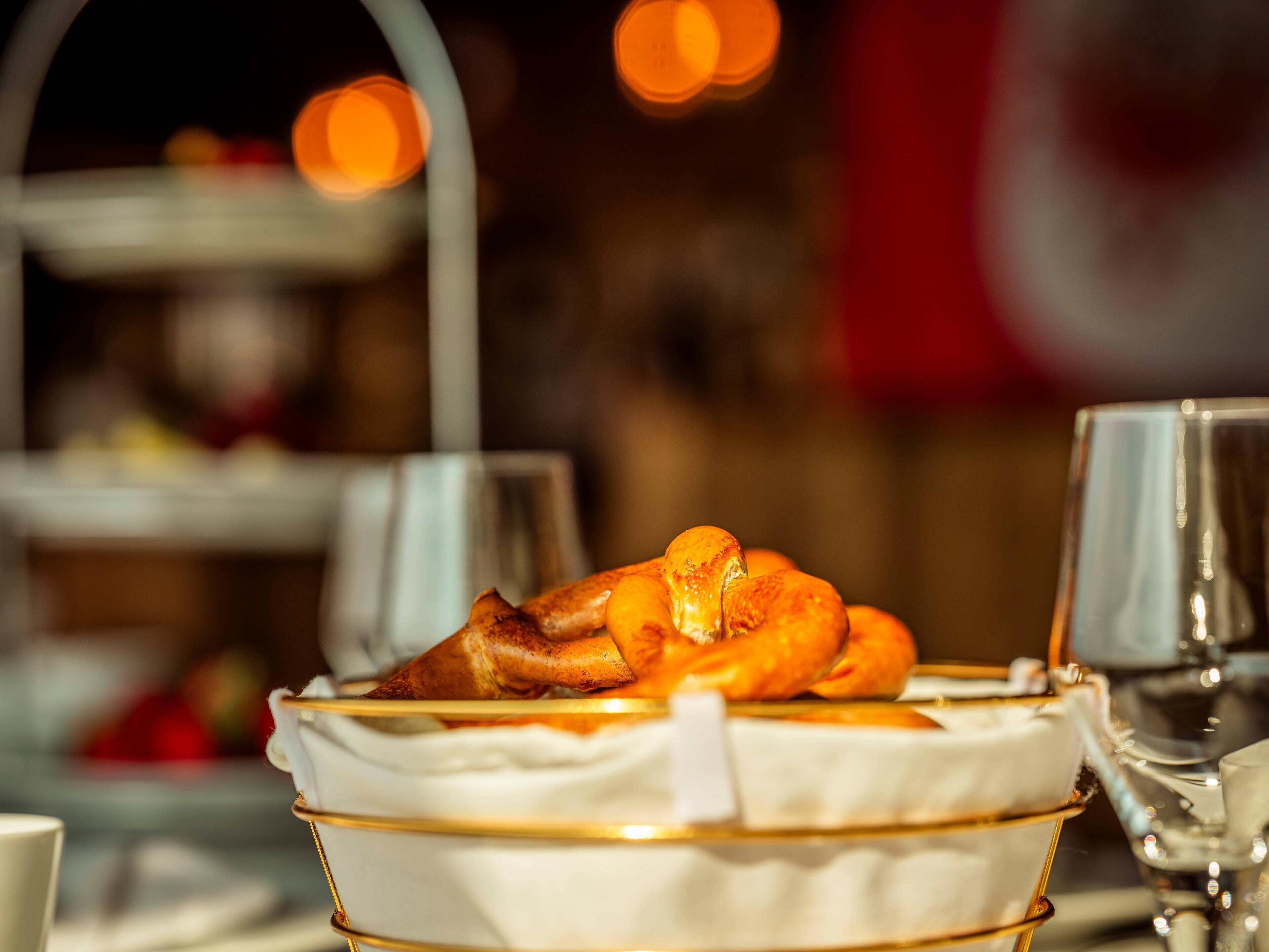 Plat de postres amb vora daurada i interior blanc, col·locat sobre una taula amb un got i una tovalla visibles.