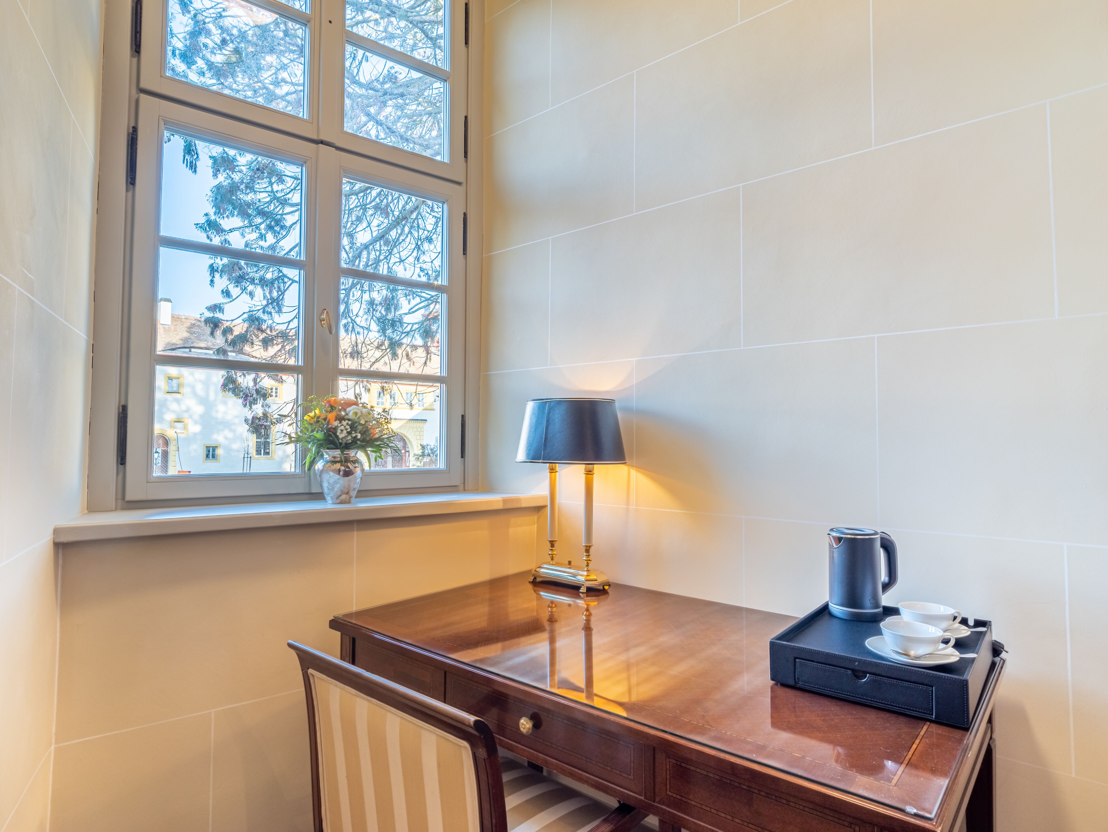 Un bureau en bois, une lampe, une machine à café et un plateau avec des tasses et des soucoupes.