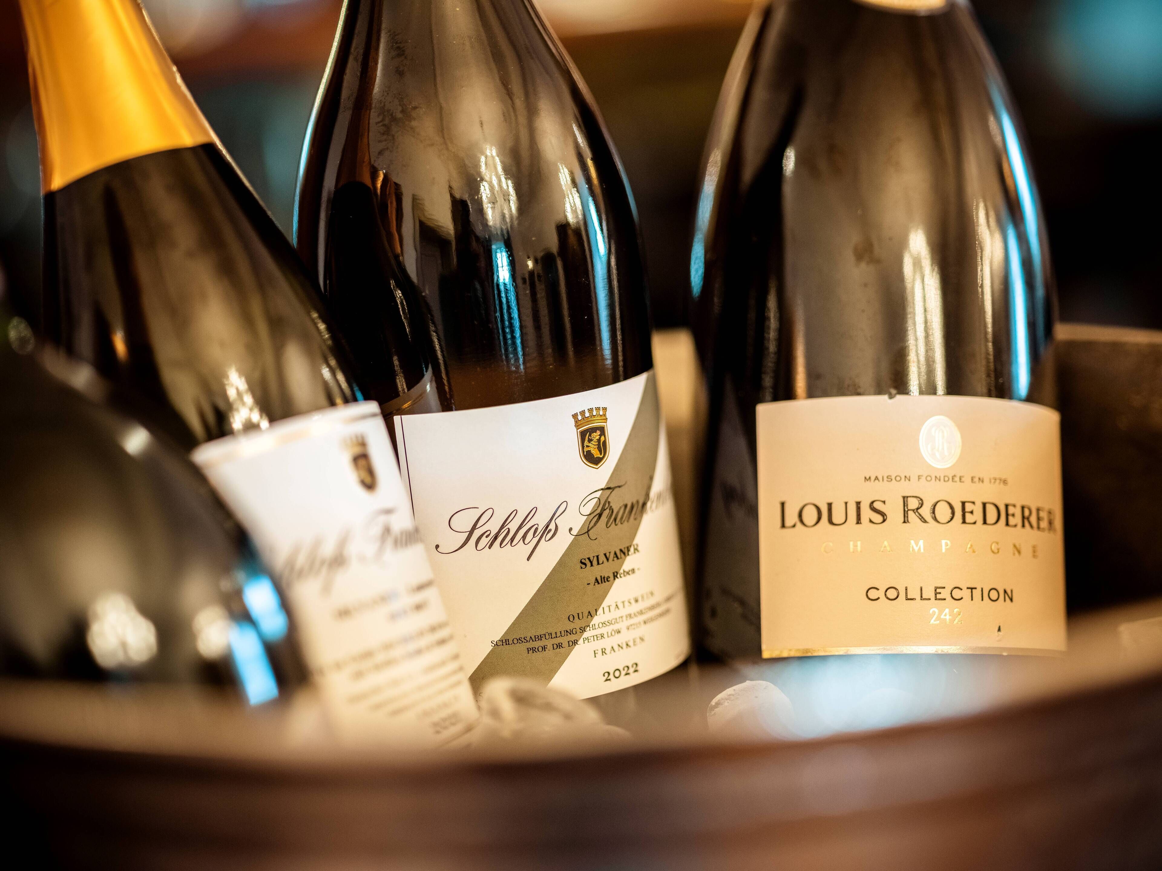 Three wine bottles with labels, one of which is labeled 'Louis Roederer Collection 2022'.