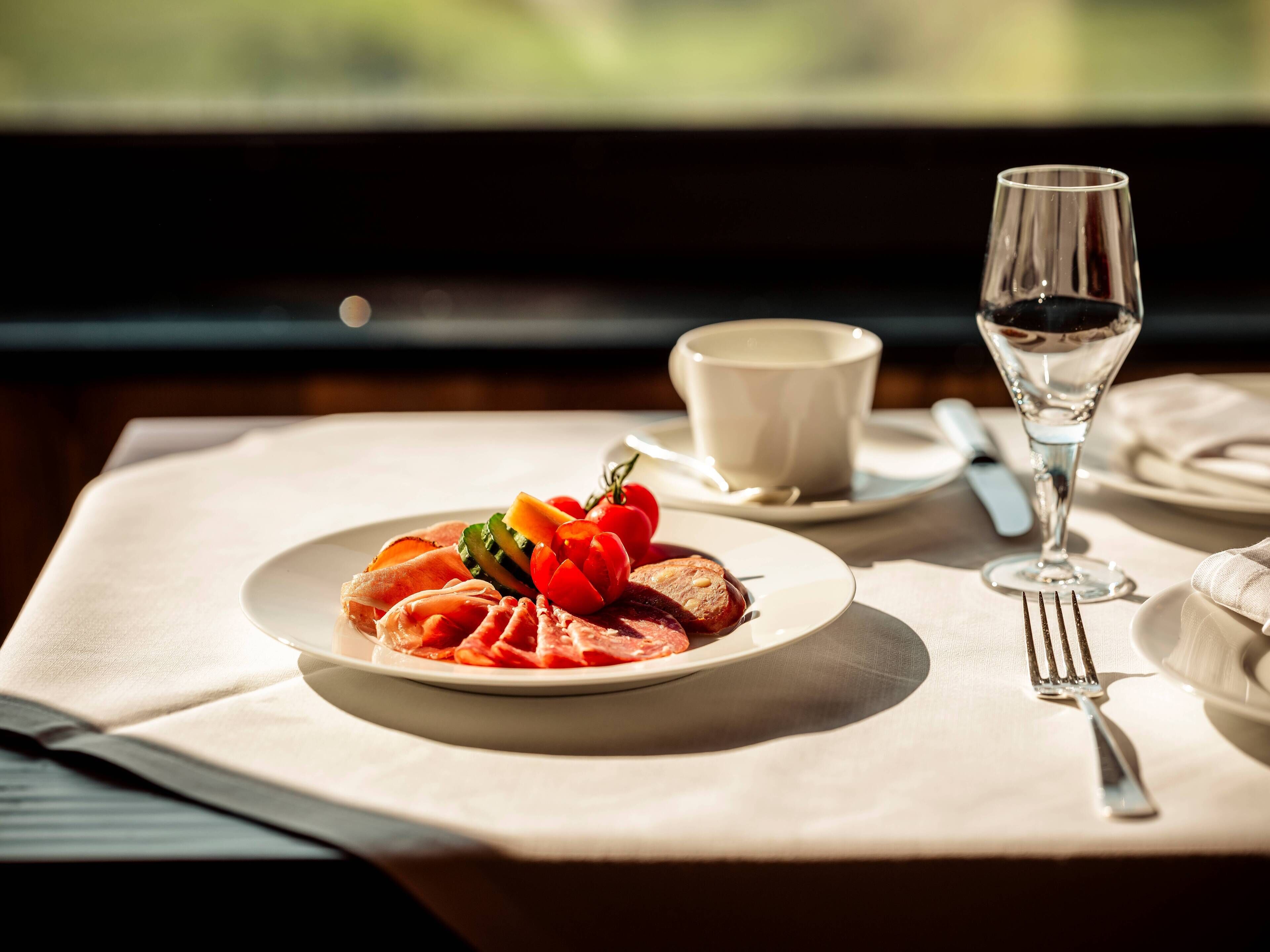A dining table with a plate of food, a cup, and a wine glass.