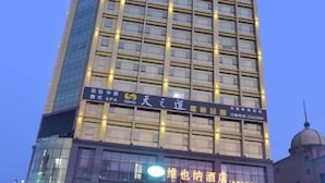 Een hoog gebouw met meerdere verdiepingen, met verlichte ramen en een opvallend bord.