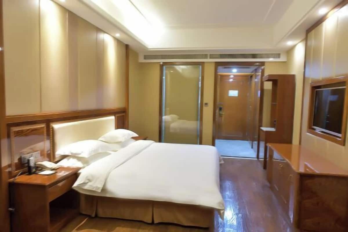 Une chambre d’hôtel avec un lit, une table de chevet et un téléviseur.