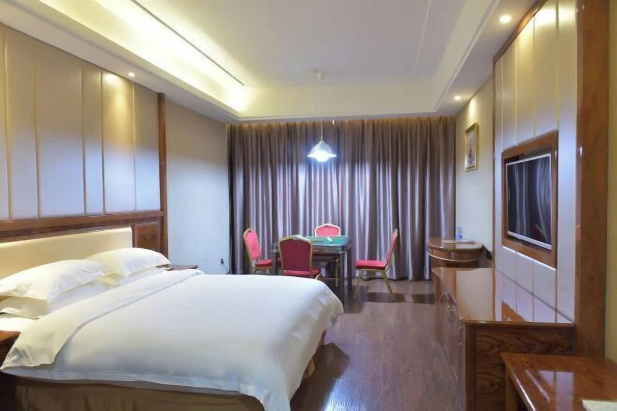 Une chambre d’hôtel avec un lit, un bureau, une chaise, une télévision et une fenêtre.