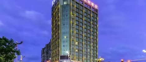A multi-story hotel with a prominent sign at the top, a glass facade, and a busy street in the foreground.