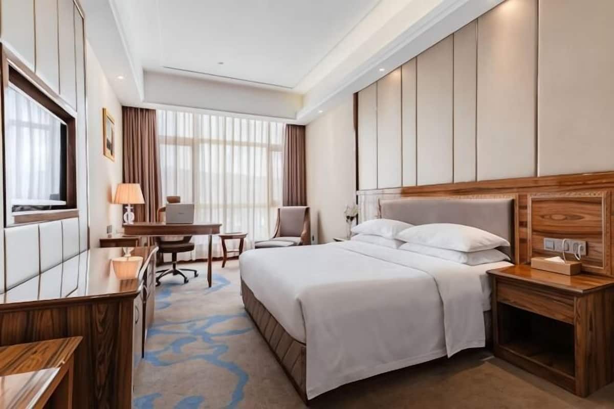 Une chambre d’hôtel équipée d’un lit, d’un bureau, d’une chaise et d’un téléviseur.