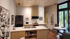 Una cocina moderna con una isla central, techo de madera y ventanas amplias.