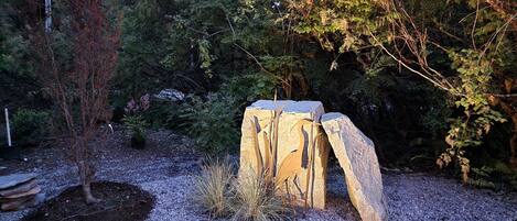 Un jardin agrémenté d’une sculpture en pierre, d’un sol recouvert de gravier et de diverses plantes.