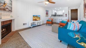 Un salon moderne doté d’une cheminée, d’un ventilateur de plafond et d’un téléviseur.
