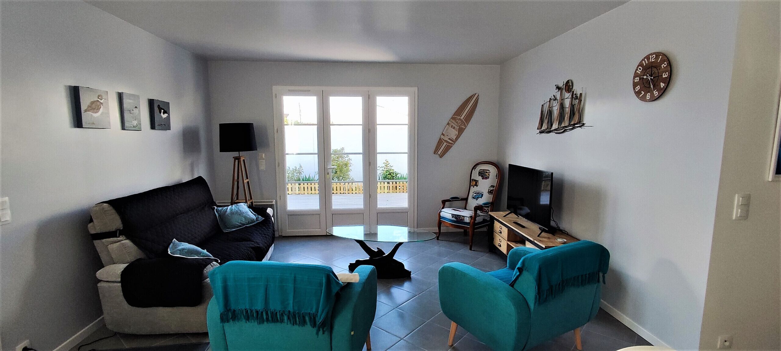 Een woonkamer met een bank, twee stoelen, een televisie en een surfboard decoratie.