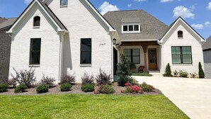 A two-story house with a gabled roof, a front porch, and a well-maintained lawn. - Visit Auburn in Style: Luxurious House on Golf Course, Perfect for Families (Auburn)