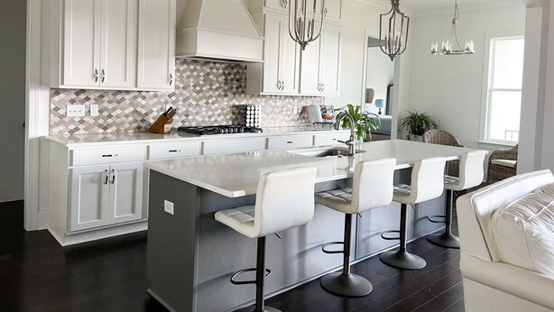 A modern kitchen with white cabinetry, a central island with bar stools, and pendant lighting. - Visit Auburn in Style: Luxurious House on Golf Course, Perfect for Families (Auburn)