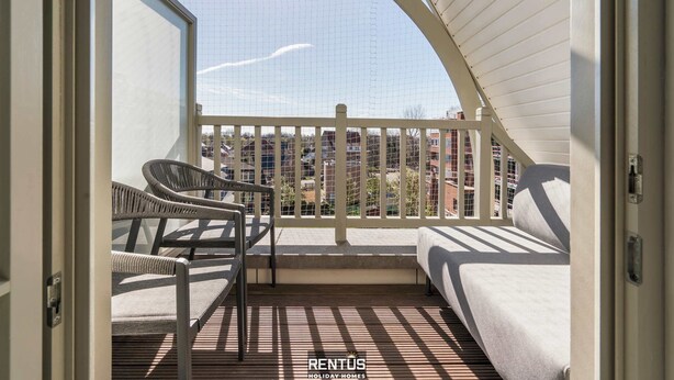 A balcony with a white railing, wicker chairs, and a sofa. - Smeysea - stylish apartment in Sint-Idesbald (Koksijde)