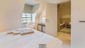 A bedroom with a large bed, a window with curtains, a fluffy rug, and a nightstand. - Smeysea - stylish apartment in Sint-Idesbald (Koksijde)