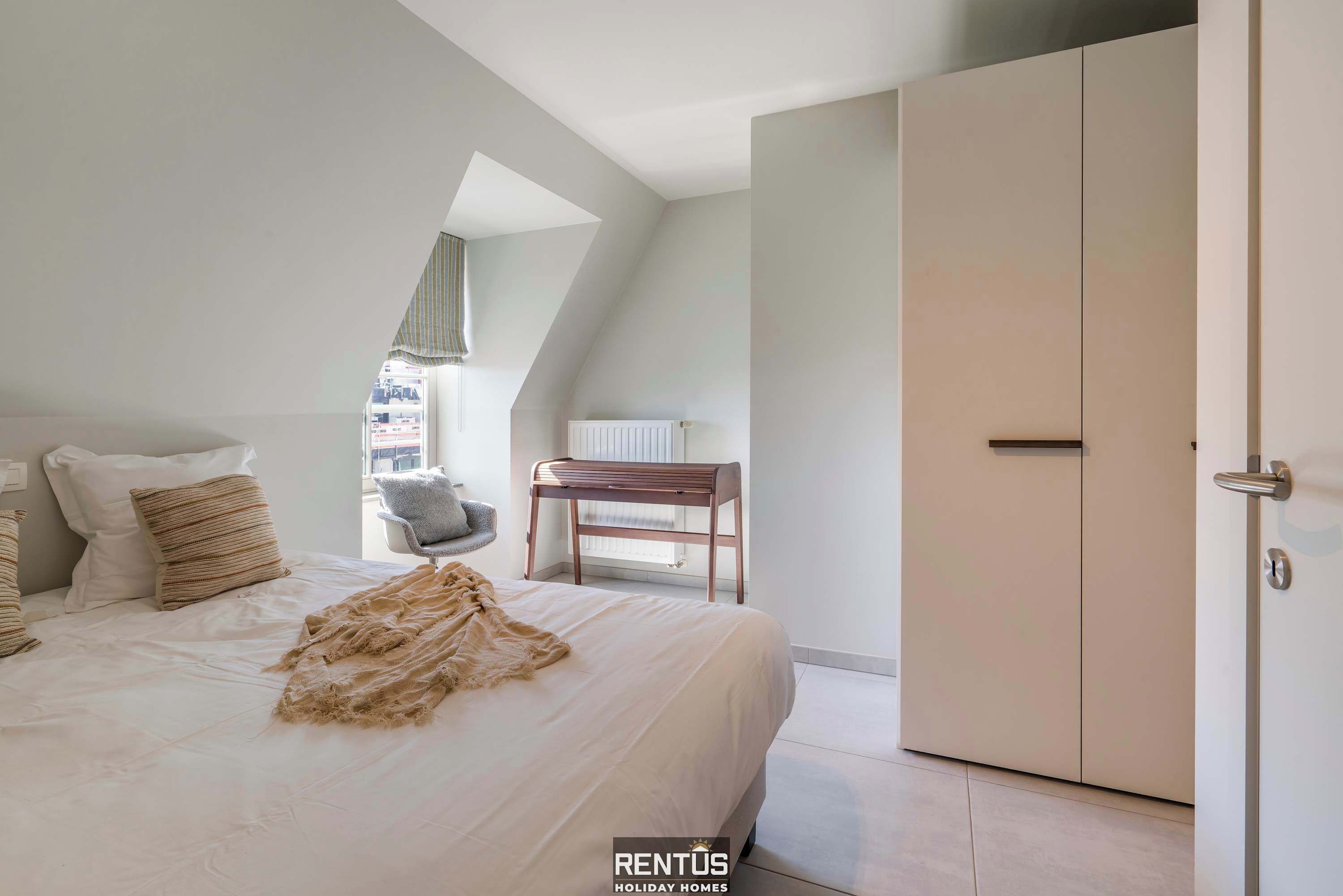 A bedroom with a large bed, a wardrobe, and a chair.