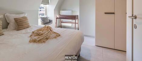 A bedroom with a large bed, a wardrobe, and a chair.