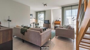 A modern living room with two sofas, a TV, and a dining area. - Smeysea - stylish apartment in Sint-Idesbald (Koksijde)