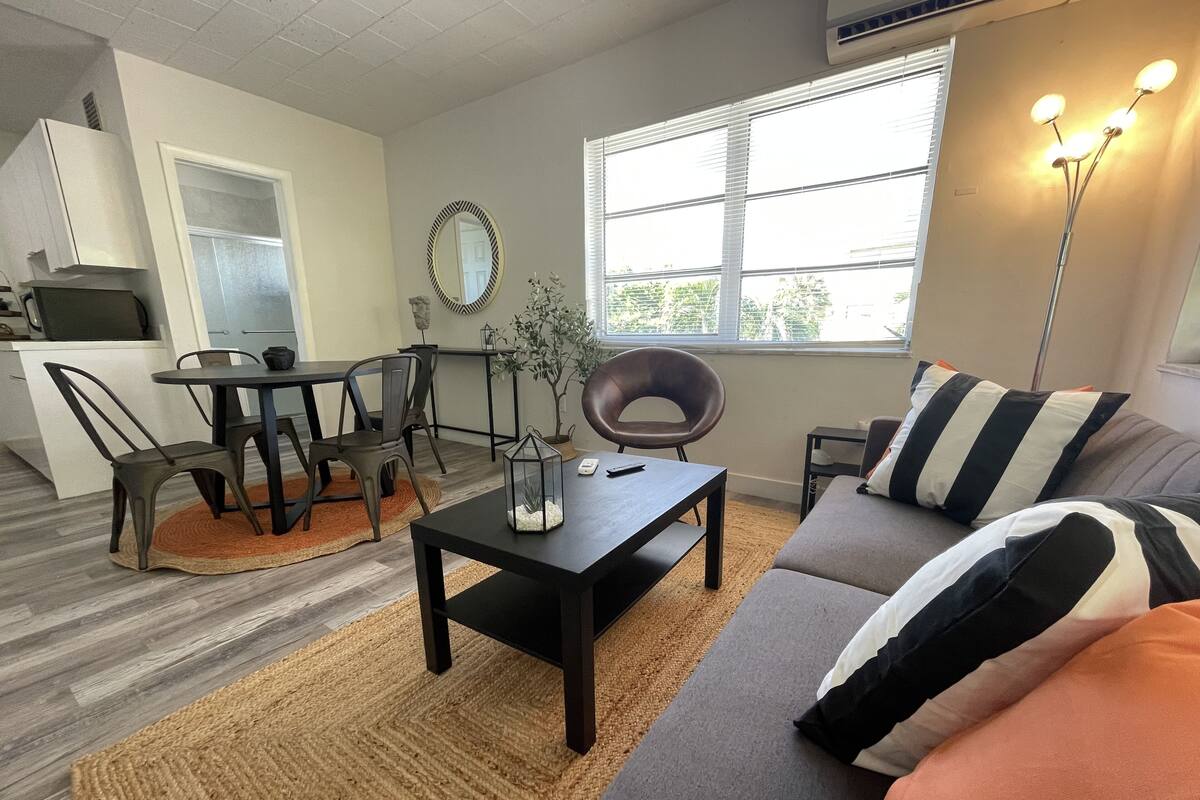 A modern living room with a sofa, coffee table, and dining area.