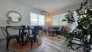 A modern living room with a dining area, featuring a sofa, chairs, a coffee table, and a large mirror.