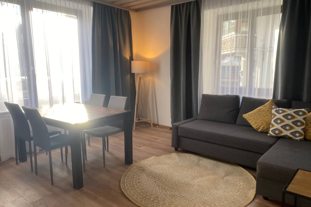 Uma sala de estar moderna com uma mesa de jantar, sofá e luminária de chão.