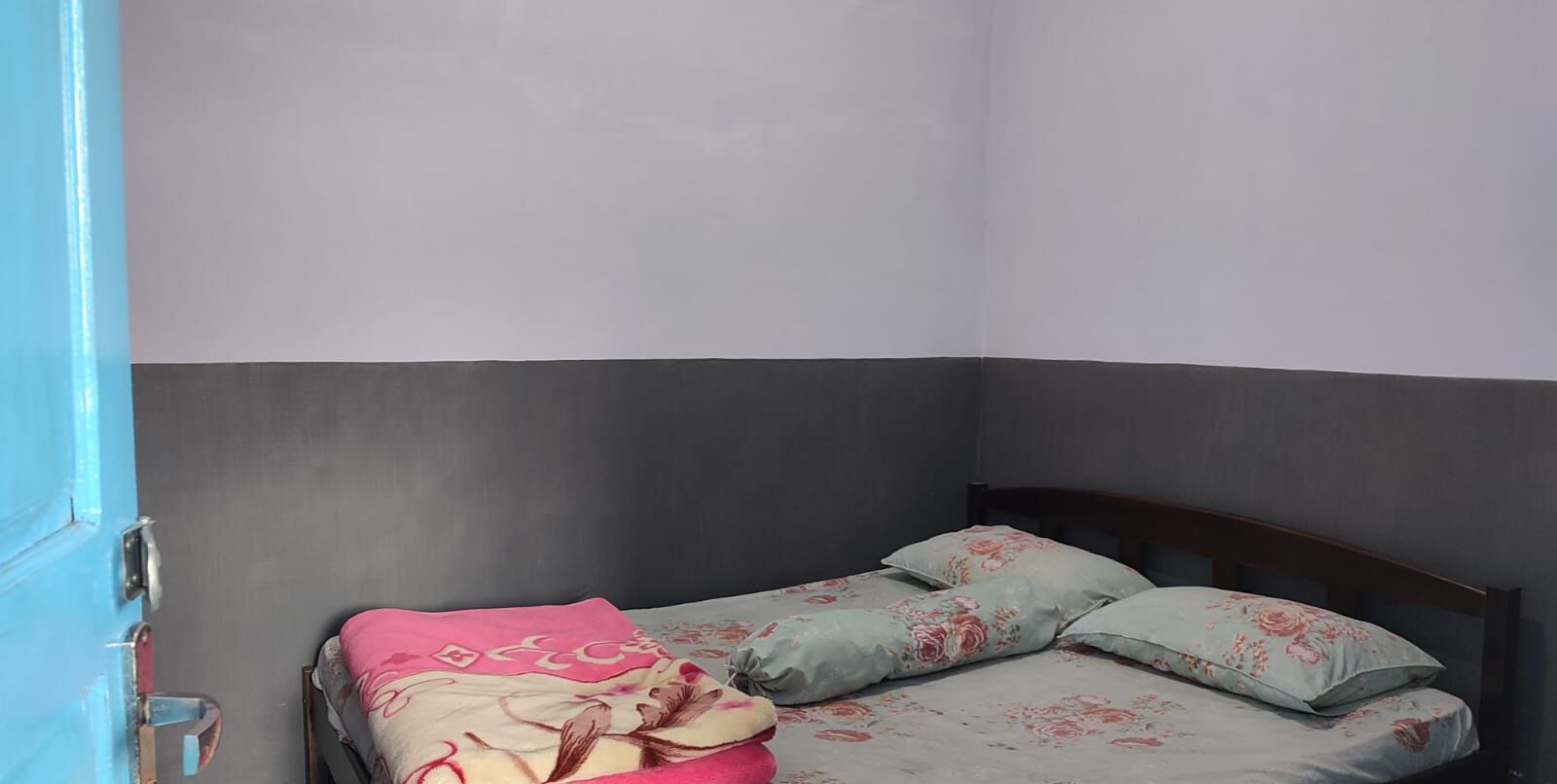 Una cama individual con ropa de cama floral y una puerta azul.