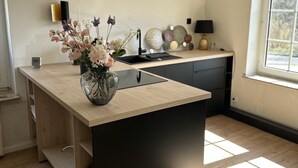 A modern kitchen with a central island, a sink, and a window providing natural light. - Apartment flying stag (Bäk)