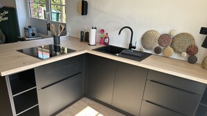 A modern kitchen with a built-in sink, black cabinets, and a light-colored countertop. - Apartment flying stag (Bäk)