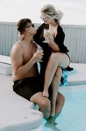 A man and a woman sitting by a poolside, holding drinks. - The Farmhouse at Bellissima Ranch (Sperry)