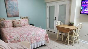 Ein Schlafzimmer mit einem Bett, einem Holztisch und einem an der Wand befestigten Fernseher.