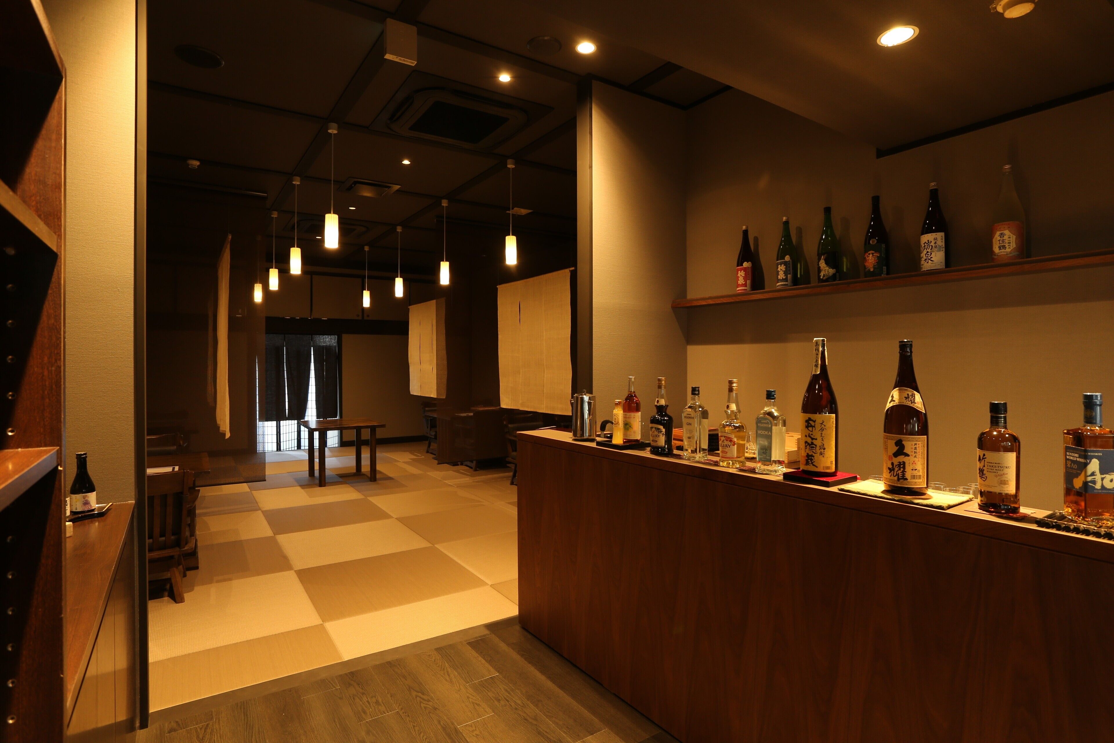 A bar area with a checkered floor, wooden counter, and various bottles.
